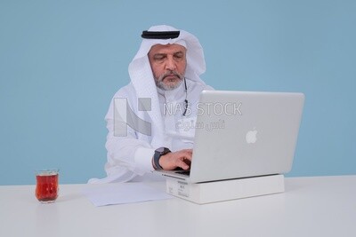 Saudi man sitting and working on a laptop, a cup of tea, business feasibility study, Saudi model