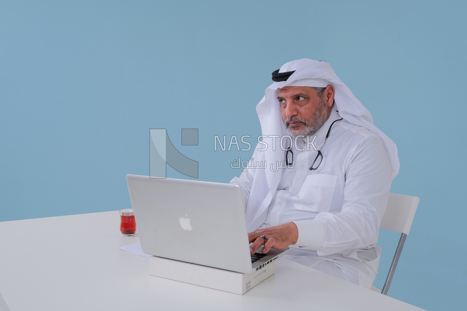 Saudi man sitting and working on a laptop, a cup of tea, business feasibility study, Saudi model