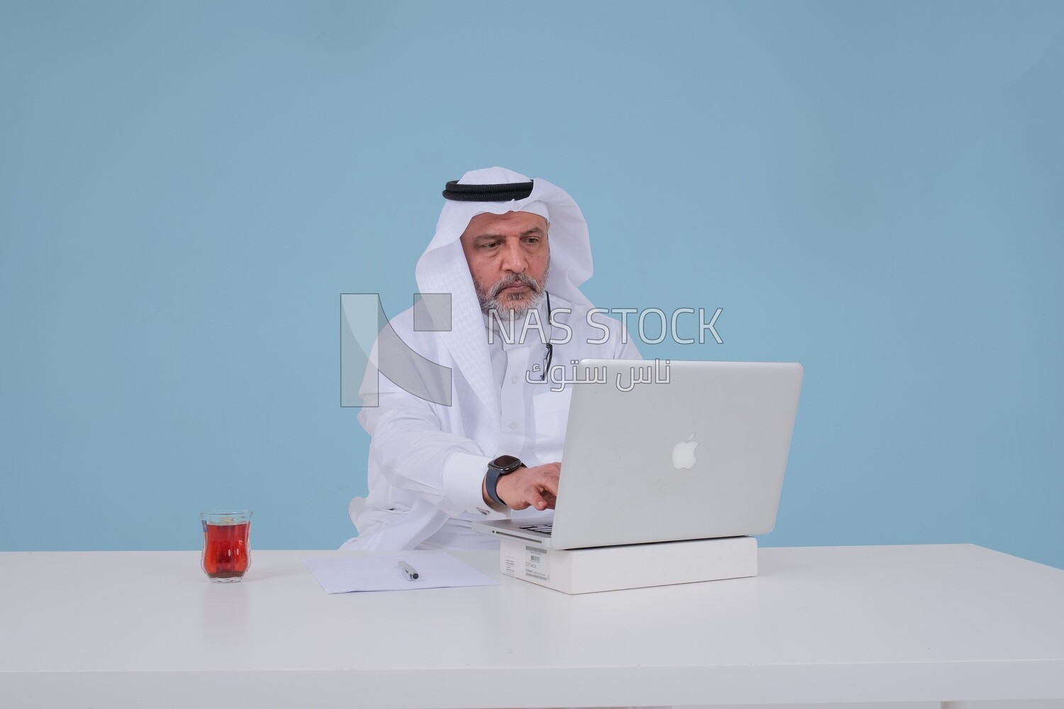 Saudi man sitting and working on a laptop, a cup of tea, business feasibility study, Saudi model