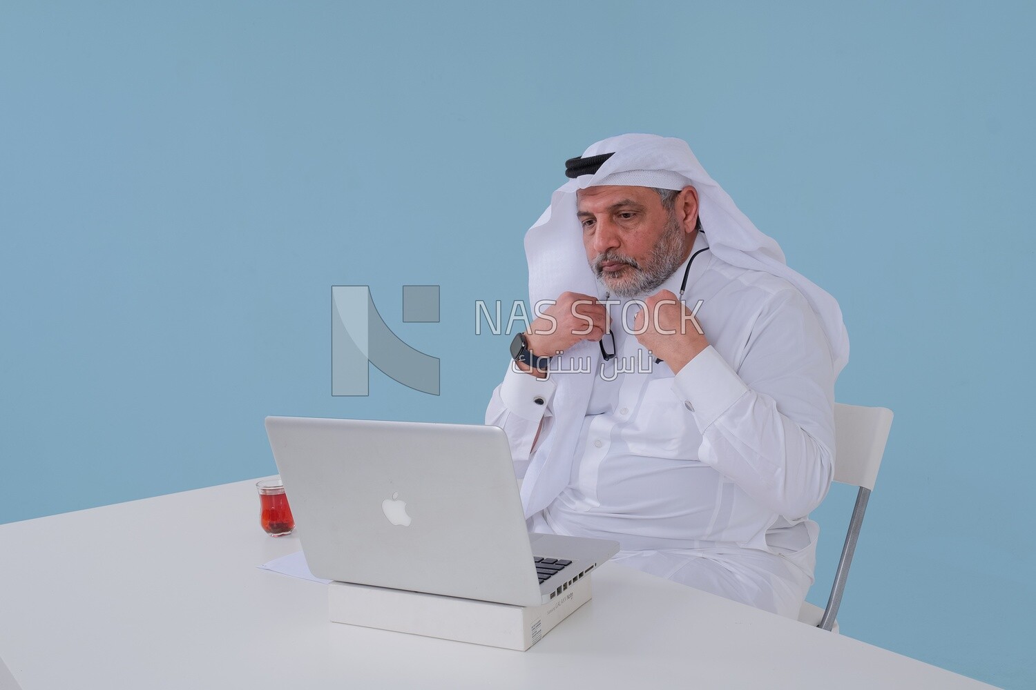 Saudi man sitting and working on a laptop, a cup of tea, business feasibility study, Saudi model