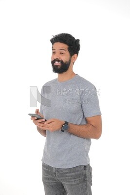 Saudi man wearing casual clothes looking away, carrying his mobile phone, Saudi model , white background