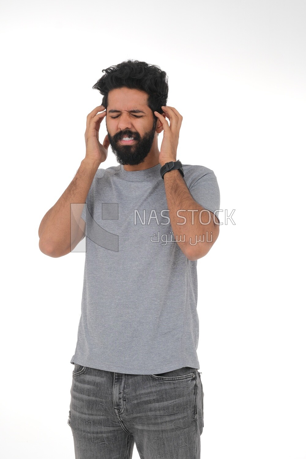Saudi man wearing casual clothes putting his hands on his ears, facial and hands gestures indicating discomfort from sounds, intolerance to noise