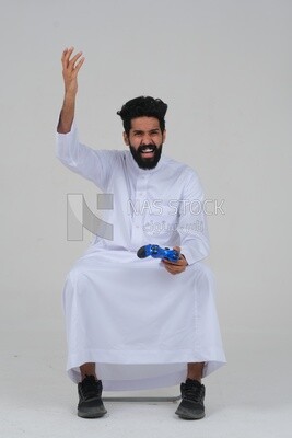 saudi  man holding a joystick in his hand and playing video games, with gestures and expressions that indicate focus and harmony, fun and entertainment with video games, PlayStation entertainment ga