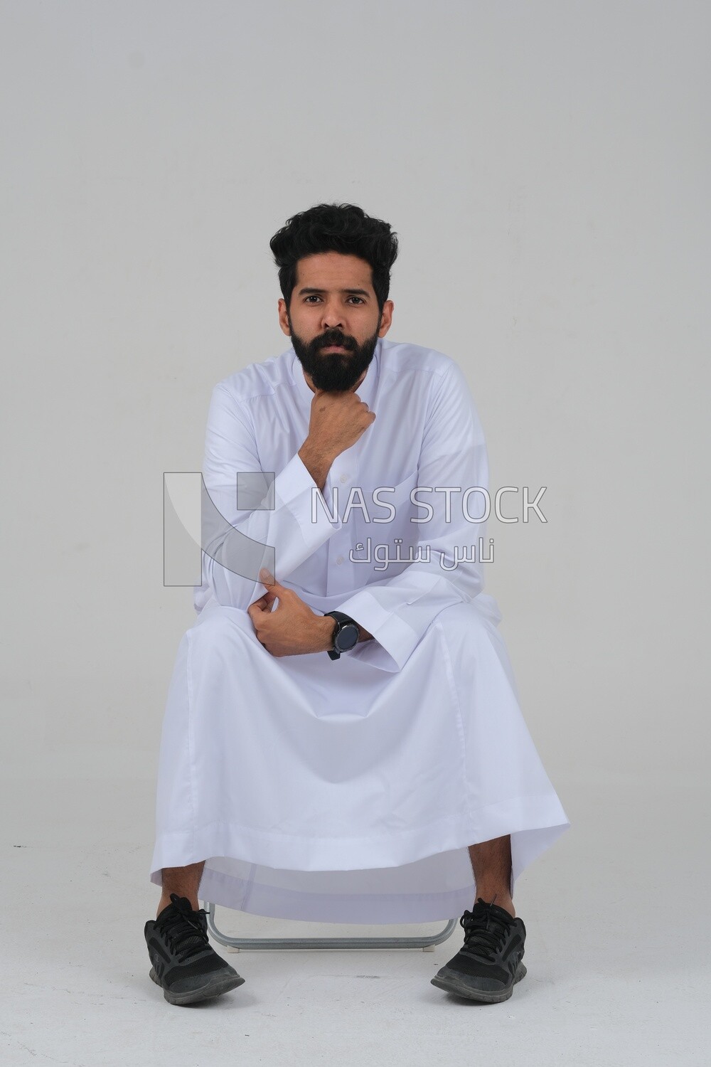 close-up of a Saudi man in traditional Saudi dress, sitting on a chair, Saudi model, white background