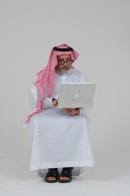 old Saudi man sitting in front of a laptop, business feasibility study, white background, Saudi model
