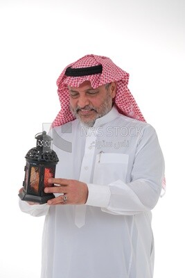 رجل سعودي يحمل فانوس رمضان ، فانوس رمضان ، شهر رمضان المبارك ، اضاءة وزينة لشهر رمضان ، اجواء رمضانية ، مناسبات دينية.