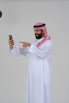 رجل سعودي يستخدم هاتف محمول ، يتواصل مع الأفراد ، طلبات وتسويق عبر الإنترنت ، علاقات اجتماعية ، باستخدام أجهزة تقنية ، خلفية بيضاء