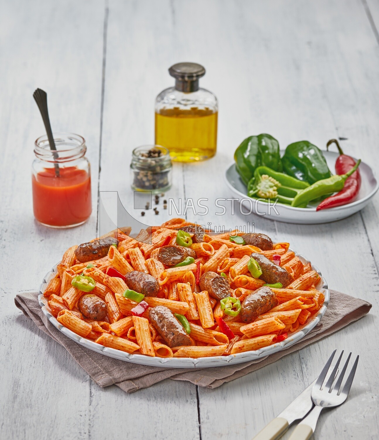 Side view of a dining table containing pasta, sausage and appetizers