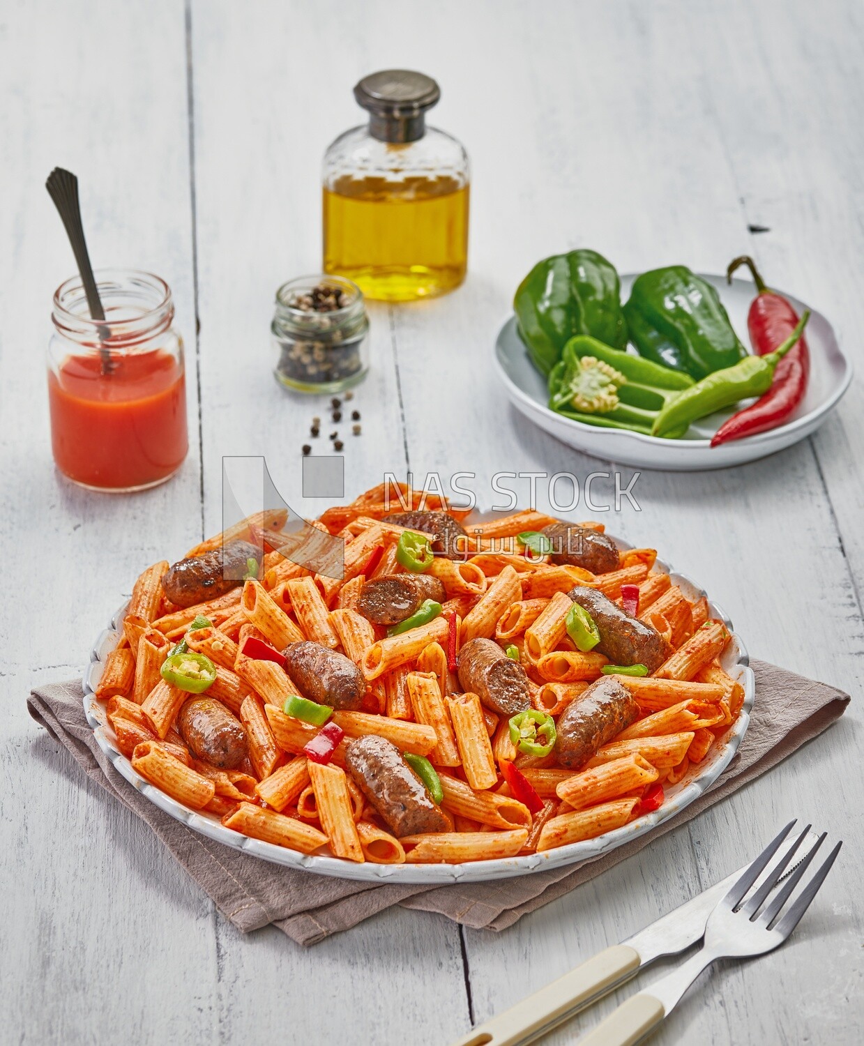 Top view of a dining table containing pasta with sausage and appetizers