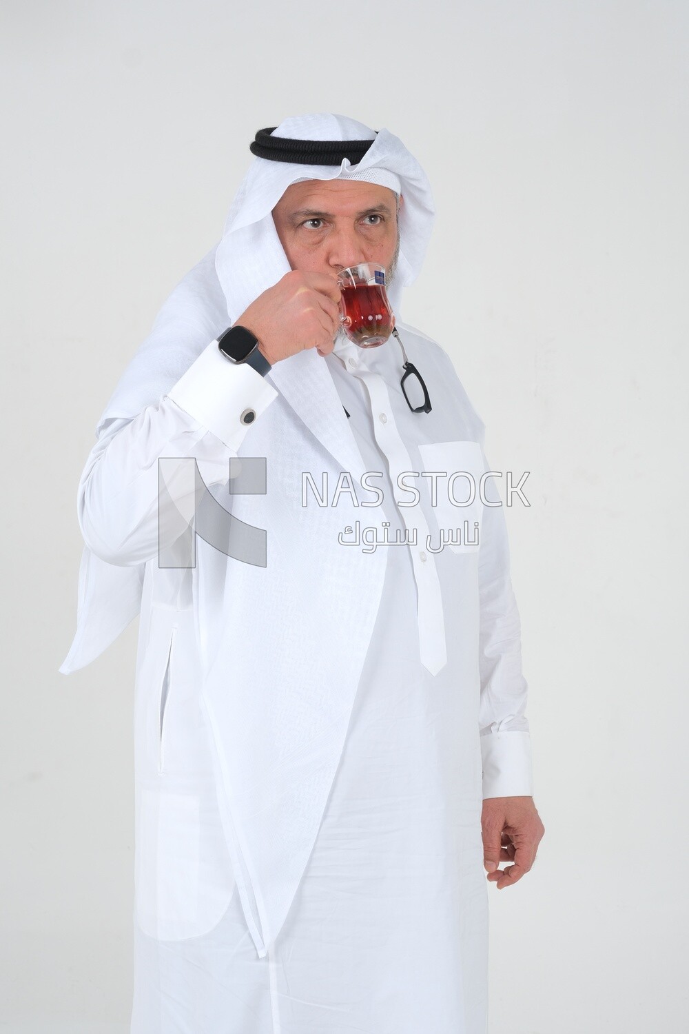 old Saudi man wearing a white dress, drinking a cup of tea, self-confidence, white background, Saudi model