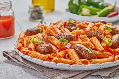 Side view of a plate of pasta with sausage and appetizers