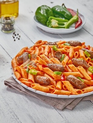 Side view of a plate of pasta with sausage and appetizers