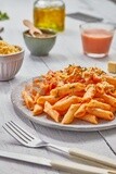 Side view of a dining table with a plate of pasta in red sauce