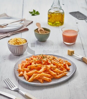 Side view of a dining table with a plate of pasta in red sauce