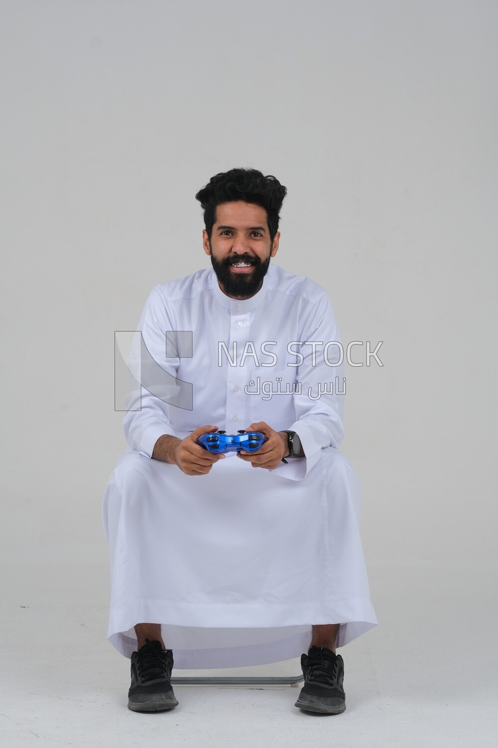 saudi  man holding a joystick in his hand and playing video games, with gestures and expressions that indicate focus and harmony, fun and entertainment with video games, PlayStation entertainment ga