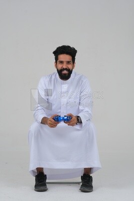 saudi  man holding a joystick in his hand and playing video games, with gestures and expressions that indicate focus and harmony, fun and entertainment with video games, PlayStation entertainment ga