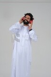 Saudi man puts on a headset and enjoys listening to songs and music, recording songs and audios, voiceover, presenting radio programs, talent and art, white background, Saudi model