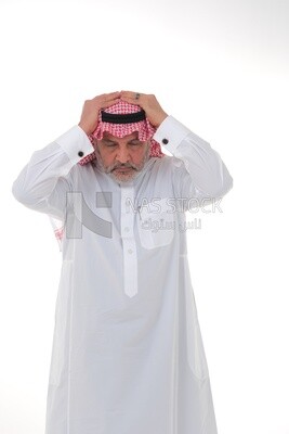 elderly Saudi man with his hands on his head, feeling pain and headache, wearing a white dress with a shemagh and headband, white background, an elderly man with pain in his head, the concept of bo