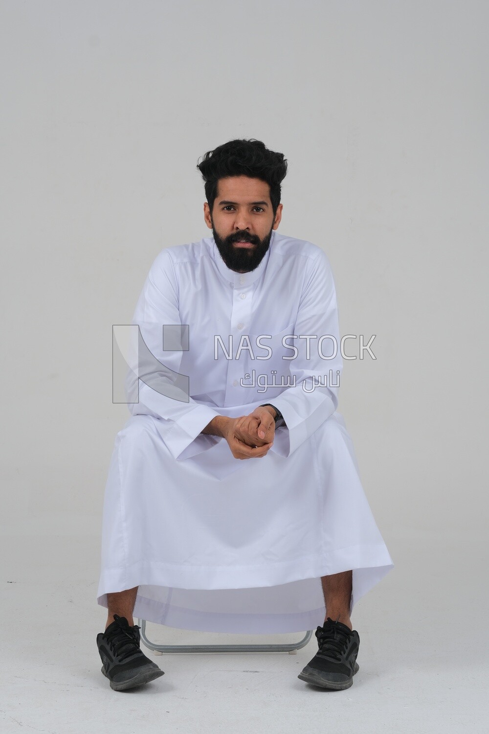 close-up of a Saudi man in traditional Saudi dress, sitting on a chair, Saudi model, white background