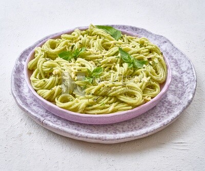 Pesto pasta with basil on a solid background
