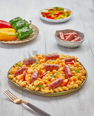 Side view of a dining table containing pasta with sausage and appetizers