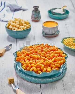 View of a dining table containing a plate of pasta with cheese and appetizers