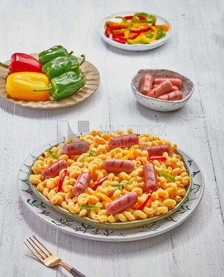 Top view of a dining table containing pasta, sausage and appetizers