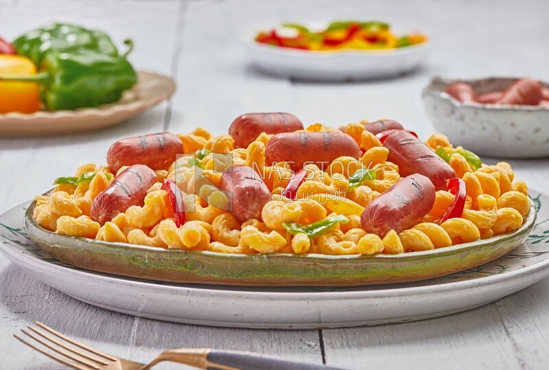 Side view of a plate of pasta with sausage and appetizers