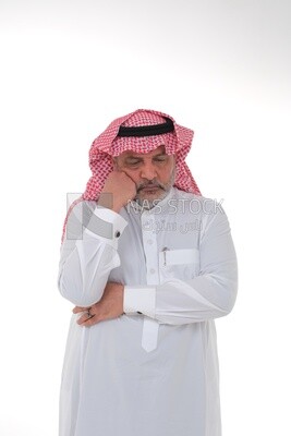 saudi man wearing a traditional Saudi dress, putting his hand on his face with gestures and facial expressions and hands indicating boredom, reflecting on a problem solution, thinking about a topic, f