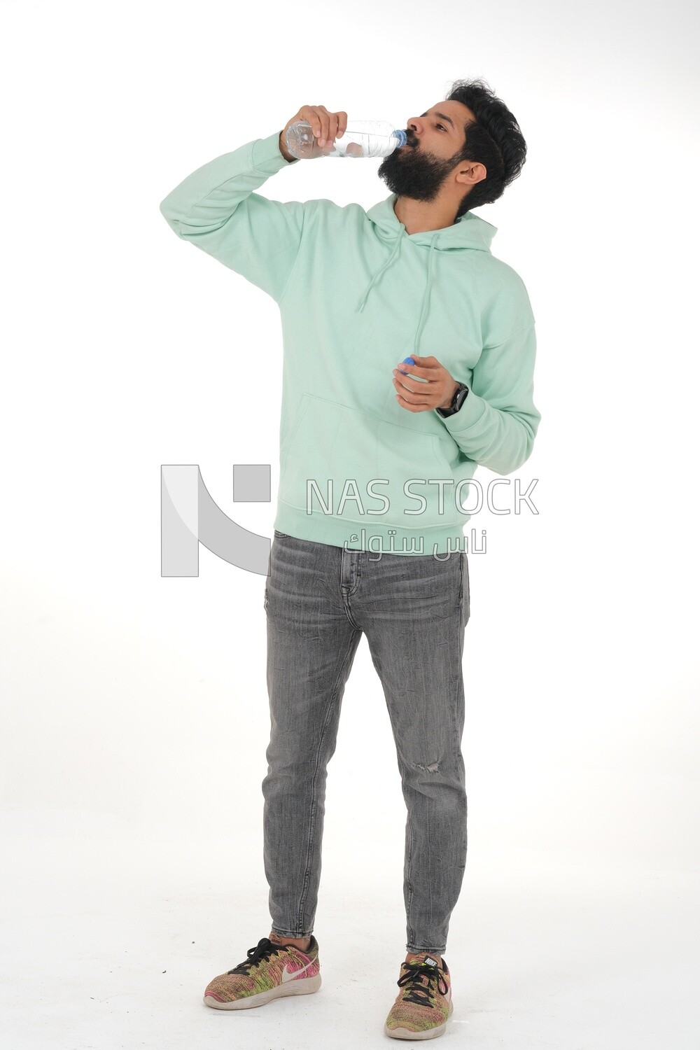 Saudi man wearing casual clothes, drinking from a water bottle, Saudi model, white background