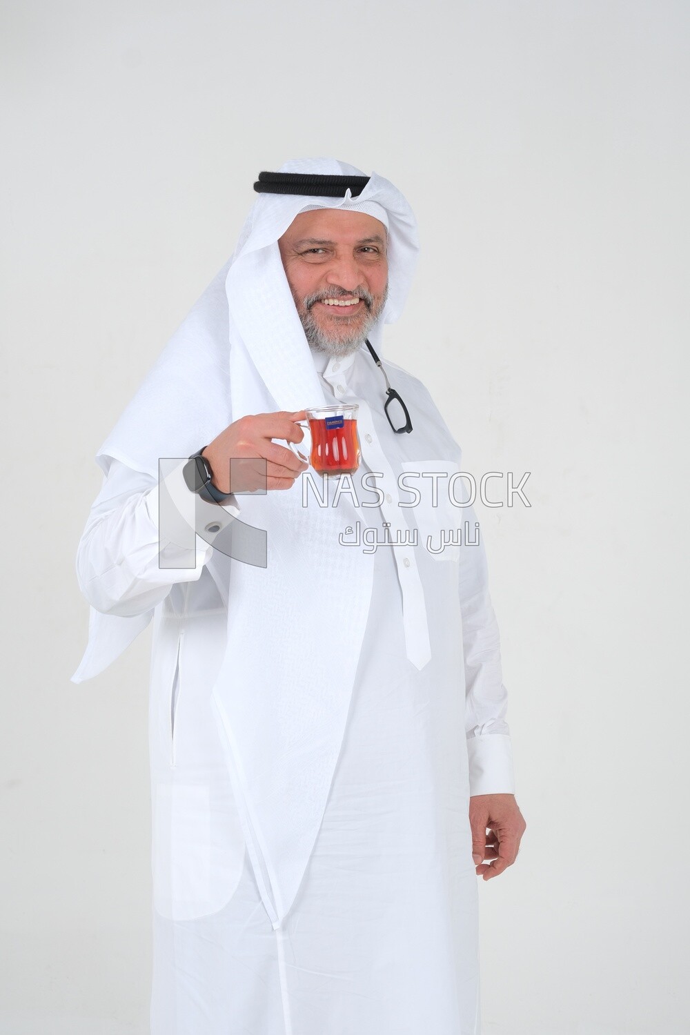 old Saudi man wearing a white dress, drinking a cup of tea, self-confidence, white background, Saudi model