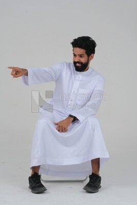 close-up of a Saudi man in traditional Saudi dress pointing away, side view, Saudi model, white background