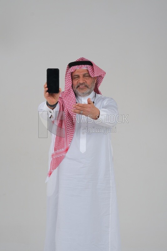 Saudi man using a mobile phone pointing on it, communicating with individuals, online requests and marketing, social relations, using technical devices, white background