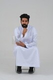 close-up of a Saudi man in traditional Saudi dress, sitting on a chair, Saudi model, white background