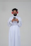 Saudi man puts on a headset and enjoys listening to songs and music, recording songs and audios, voiceover, presenting radio programs, talent and art, white background, Saudi model