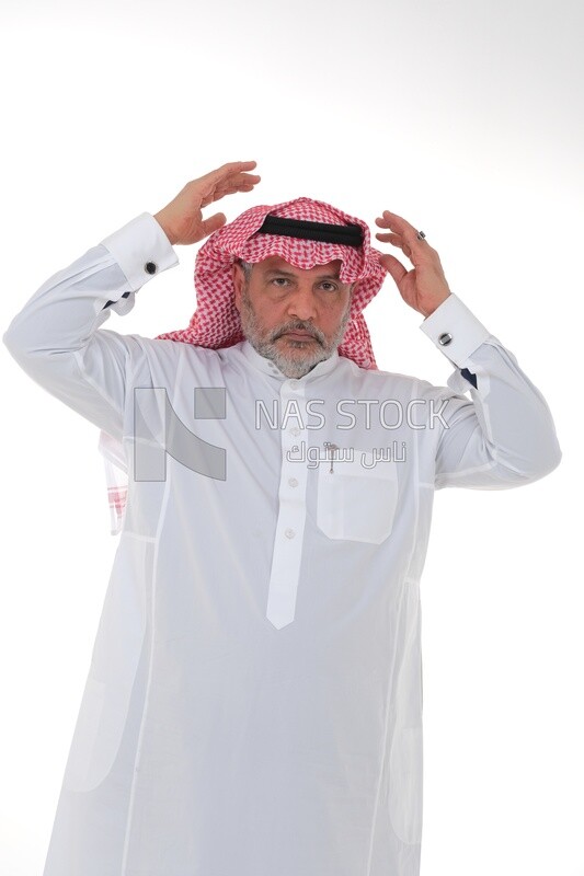 elderly Saudi man with his hands on his head, feeling pain and headache, wearing a white dress with a shemagh and headband, white background, an elderly man with pain in his head, the concept of bo