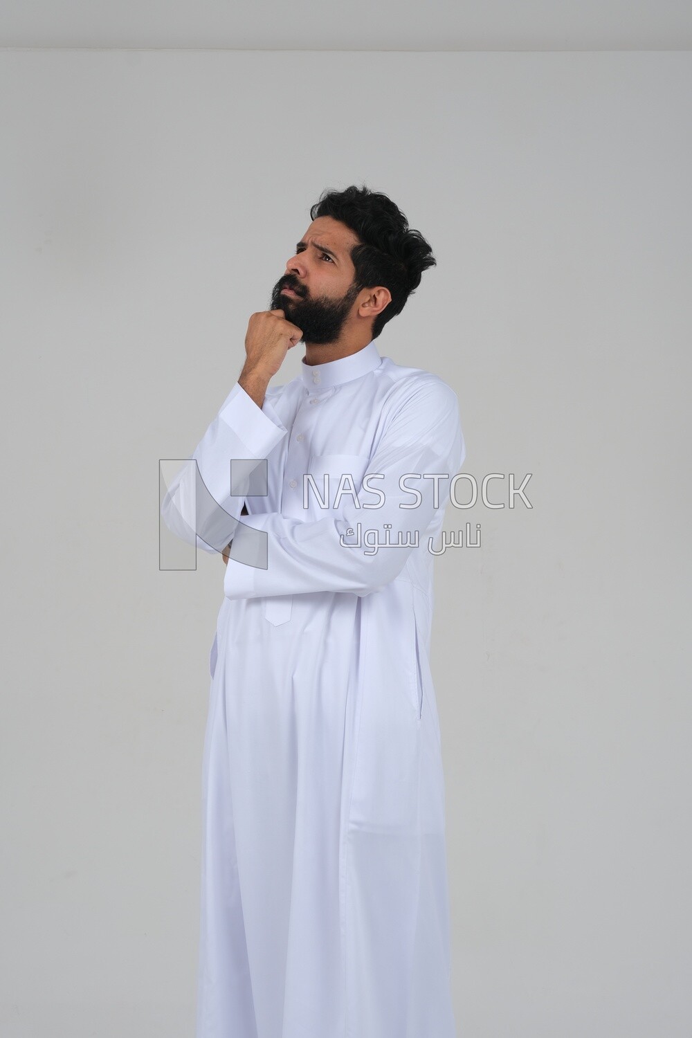 saudi man wearing a traditional Saudi dress, putting his hand on his face with gestures and facial expressions and hands indicating boredom, reflecting on a problem solution, thinking about a topic, f