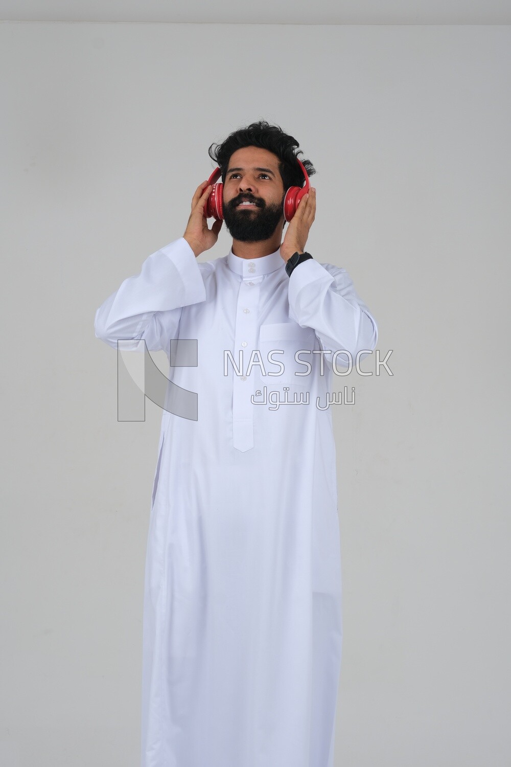 Saudi man puts on a headset and enjoys listening to songs and music, recording songs and audios, voiceover, presenting radio programs, talent and art, white background, Saudi model