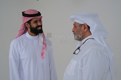 رجل سعودي يقضي الوقت مع والده واقفين معًا ، خلفية بيضاء ، موديل سعودى
