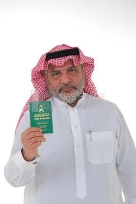 رجل سعودي مسن يحمل جواز سفر سعودي مع إيماءات السعادة ، وثائق رسمية ، السفر الدولي للمواطنين السعوديين ، اليوم الوطني السعودي ، الاحتفال باليوم الوطني ، خلفية بيضاء