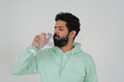 Saudi man wearing casual clothes, drinking from a water bottle, Saudi model, white background