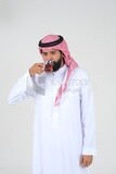 رجل سعودي يرتدي ثوبًا أبيض ، يحتسى كوبًا من الشاي ، ثقة بالنفس ، خلفية بيضاء ، موديل سعودي