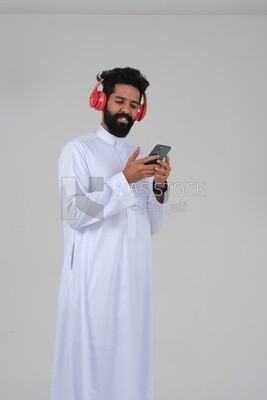 Saudi man puts on a headset and enjoys listening to songs and music, recording songs and audios, voiceover, presenting radio programs, talent and art, white background, Saudi model