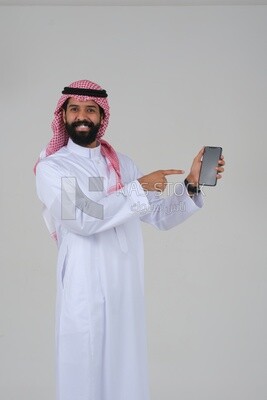Saudi man using a mobile phone pointing on it, communicating with individuals, online requests and marketing, social relations, using technical devices, white background