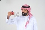 رجل سعودي يرتدي ثوبًا أبيض ، يحتسى كوبًا من الشاي ، ثقة بالنفس ، خلفية بيضاء ، موديل سعودي