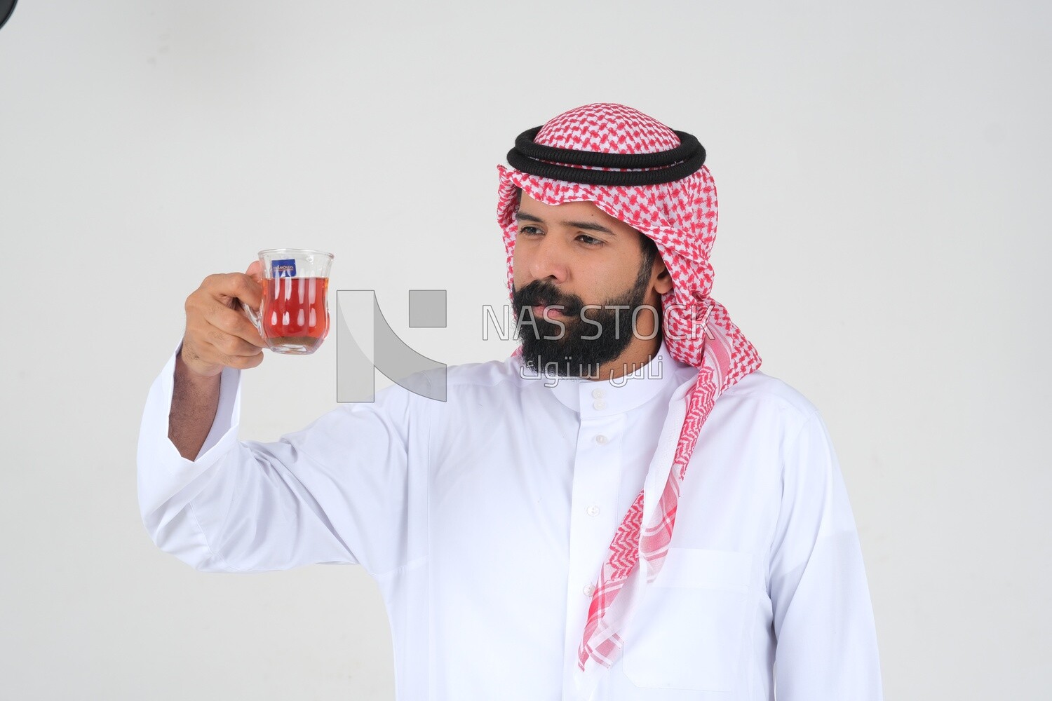 Saudi man wearing a white dress, drinking a cup of tea, self-confidence, white background, Saudi model