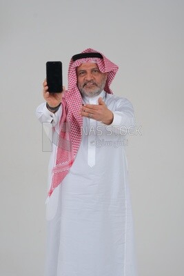 Saudi man using a mobile phone pointing on it, communicating with individuals, online requests and marketing, social relations, using technical devices, white background