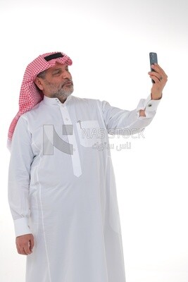 Saudi man using a mobile phone, taking a selfie, communicating with individuals, online requests and marketing, social relations, using technical devices, white background