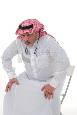 elderly Saudi man trying to sit on a chair, back and spine pain, fatigue and exhaustion, muscle spasms, health problems, white background, Saudi model