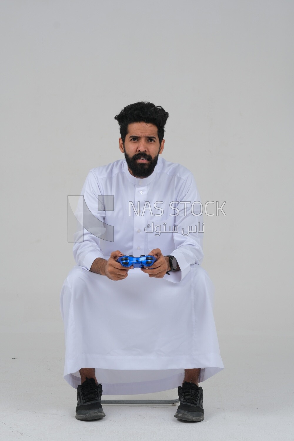 saudi  man holding a joystick in his hand and playing video games, with gestures and expressions that indicate focus and harmony, fun and entertainment with video games